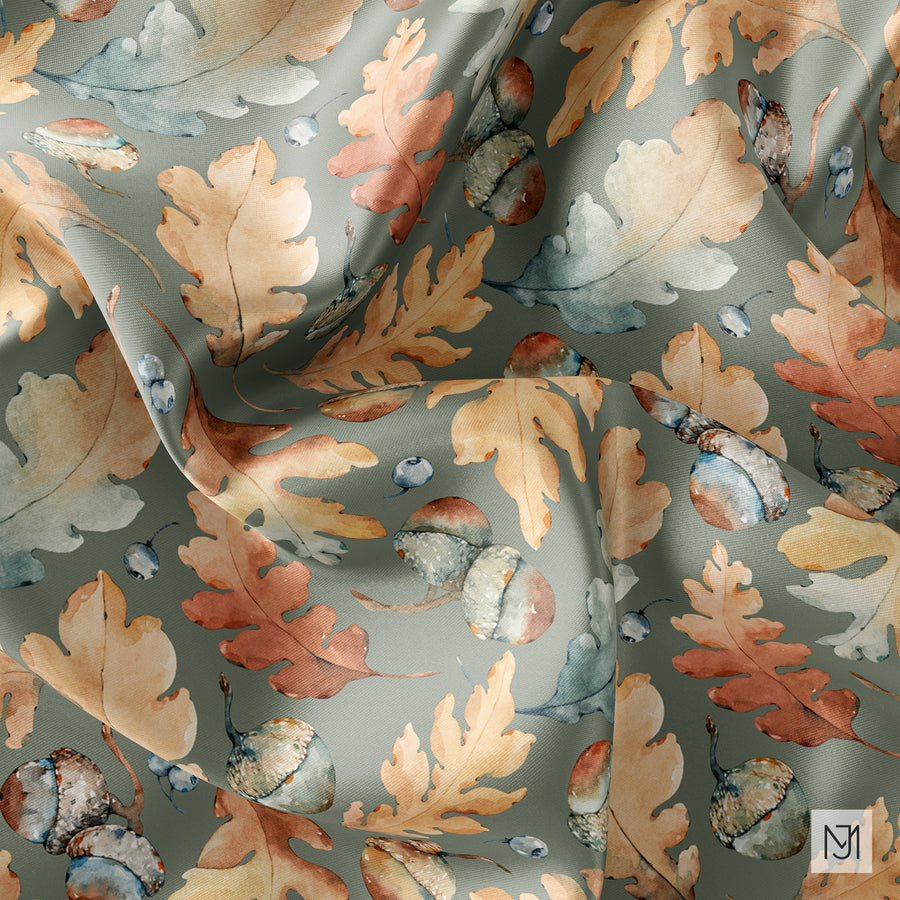 Autumn Acorns pattern shown draped on folded fabric in a sage green colorway, with the same acorns and oak leaves.