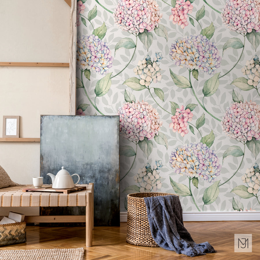 Hydrangea pattern as a wallpaper mural in a soft sage colorway, behind a woven daybed, a dark painting, and a wicker basket.