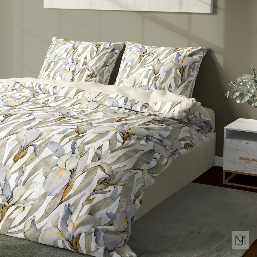 Bedroom with a duvet cover and two pillows in the iris pattern on a white background, with a nightstand and eucalyptus sprig