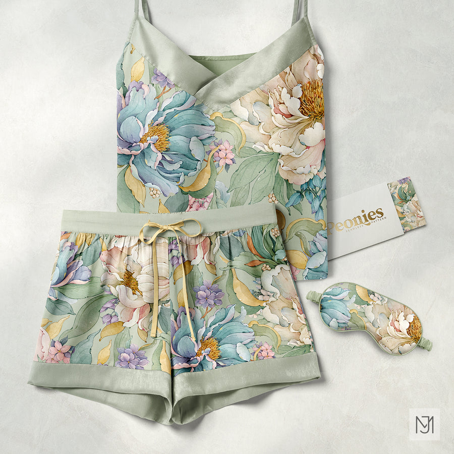 Sage green silk pajama set with a camisole top and shorts in the peonies pattern, with a matching sleep mask and branded card