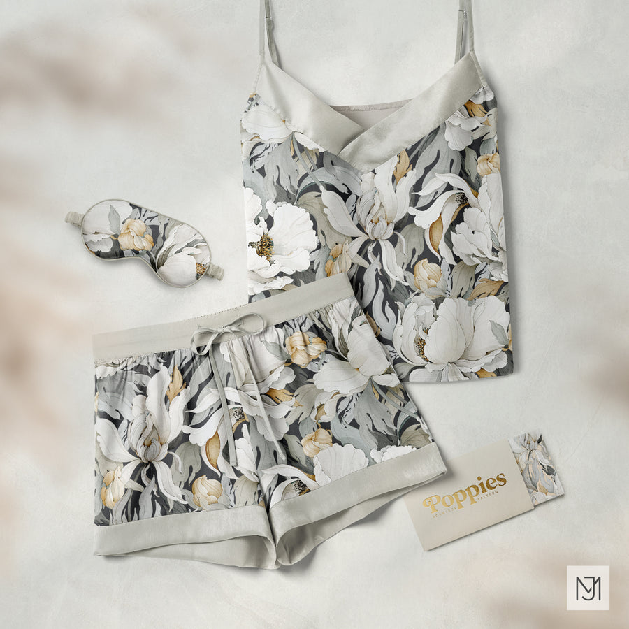 Gray silk pajama set with a camisole top and shorts in the poppies pattern, with a matching sleep mask and branded card
