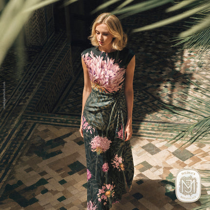 Woman wearing a cap sleeve dress printed with the Quiet Garden pattern in a dark teal colorway with pink blooms