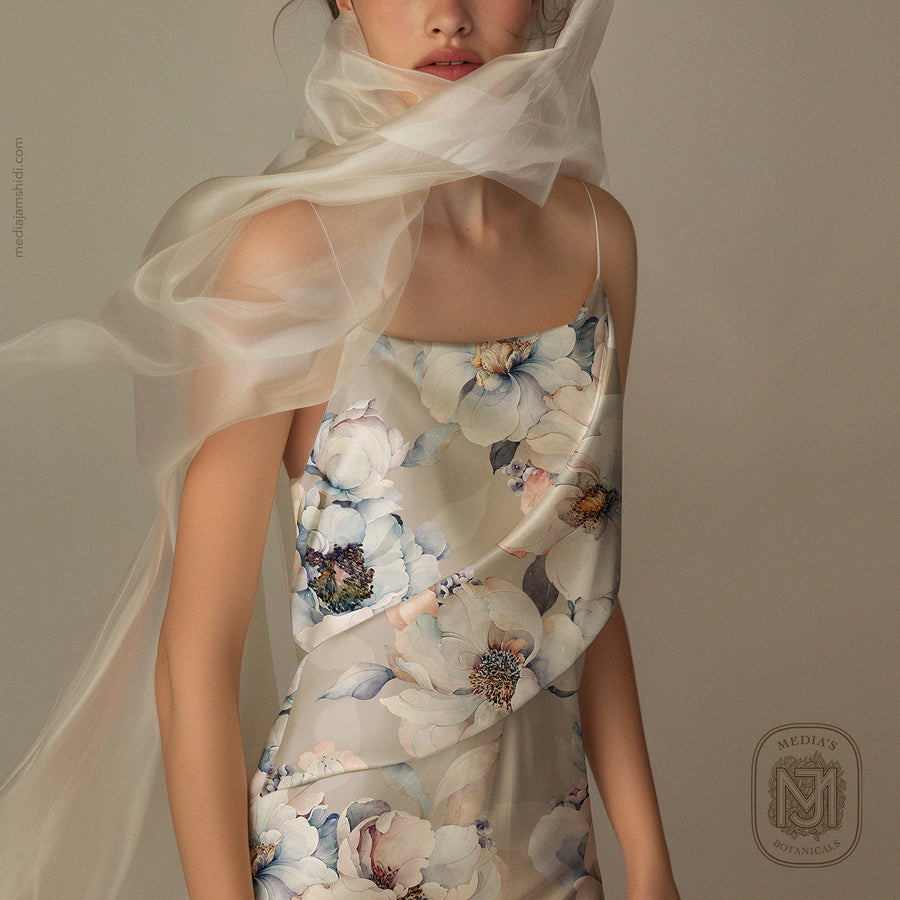 Close up of a cream silk slip dress in the Velvet Bloom pattern with a sheer scarf draped over the shoulder
