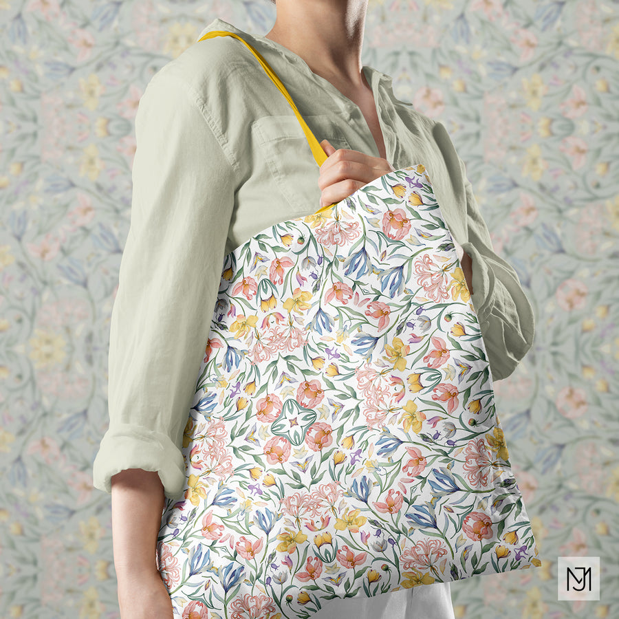 Tote bag with a yellow strap in the botanical pattern's white colorway, held by a person in a sage green shirt