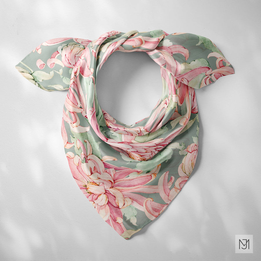 Chrysanthemum pattern printed on a silk scarf, tied in a loose knot, in a sage green colorway.