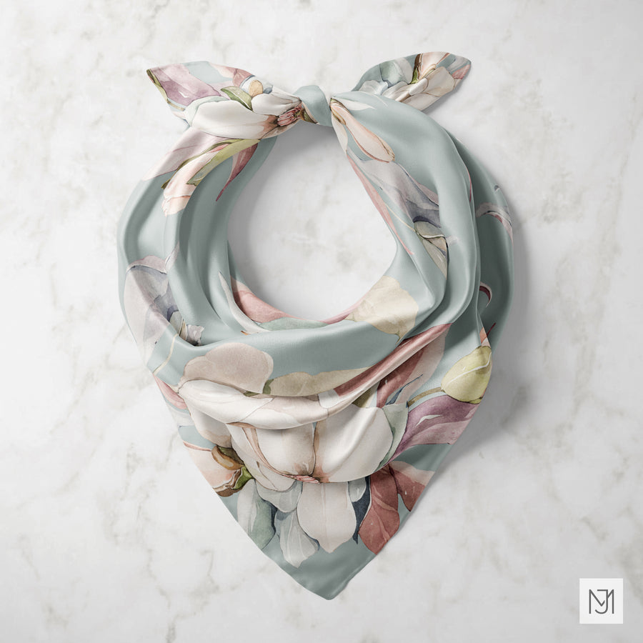Watercolor Magnolia pattern printed on a silk scarf, tied in a loose knot and shown against white marble.