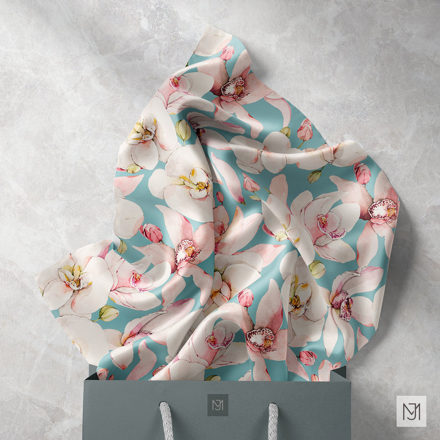 Orchids pattern printed on fabric draped inside a gift bag, in a teal colorway with the same white and pink orchids.