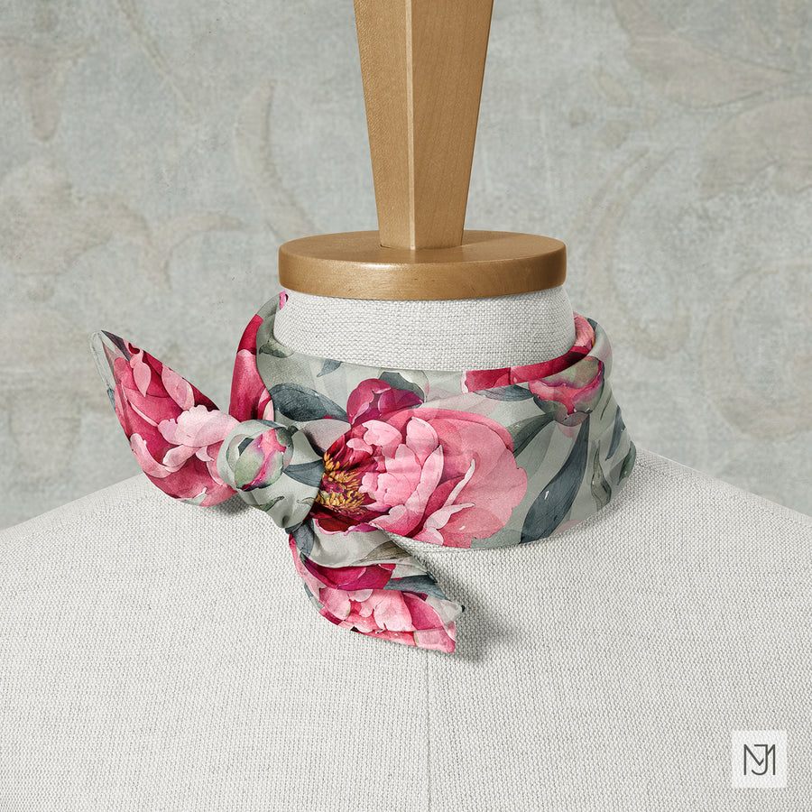 Scarf tied in a bow around a dress form mannequin's neck in a sage gray colorway of the red peonies pattern