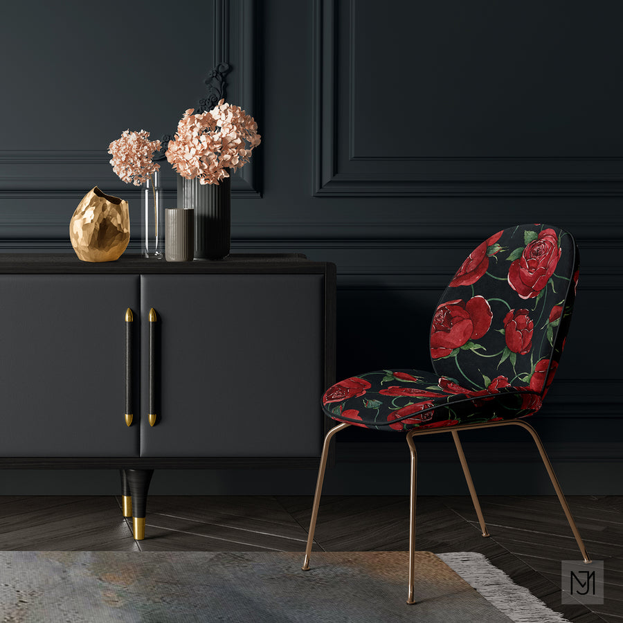 Red Roses pattern upholstered on a curved chair in a dark navy colorway, shown in a moody room with a black sideboard and dried pink hydrangeas.