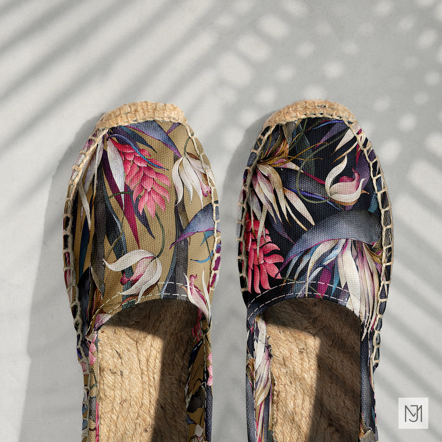 Pair of espadrille shoes in the tropical pattern, one in a tan colorway and one in a dark navy colorway