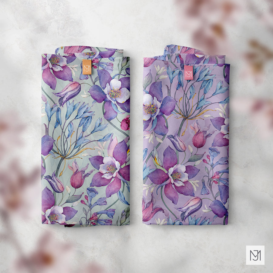 Two folded fabric swatches in the Spring Garden pattern, one in a sage green colorway and one in a lavender colorway