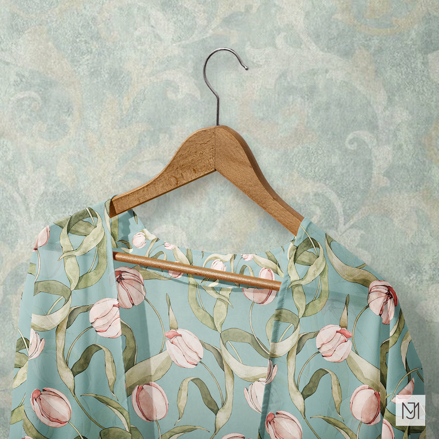 Tulips pattern on a sheer blue-gray blouse, hanging on a wood hanger against a mottled blue-green wall.