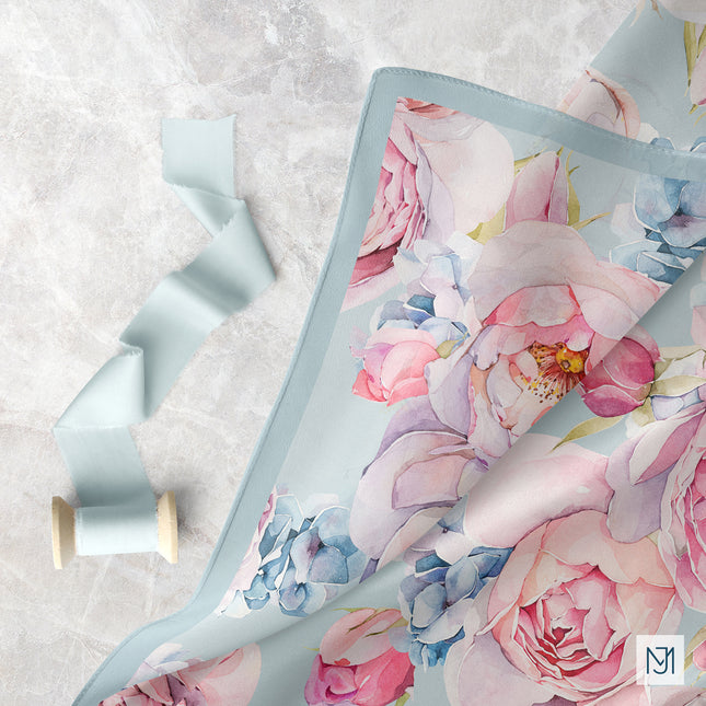 Vintage Roses pattern on draped pale blue fabric, with a matching ribbon spool beside it.